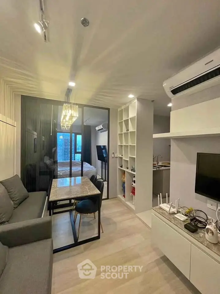 Modern living room with sleek design, featuring a cozy sofa, dining table, and wall-mounted TV in a compact apartment.