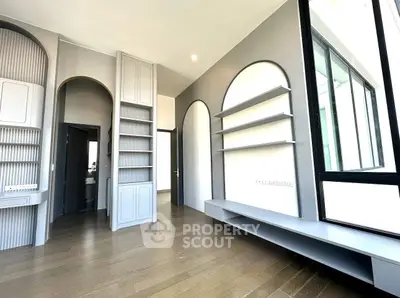 Spacious modern living room with large windows and stylish built-in shelves.