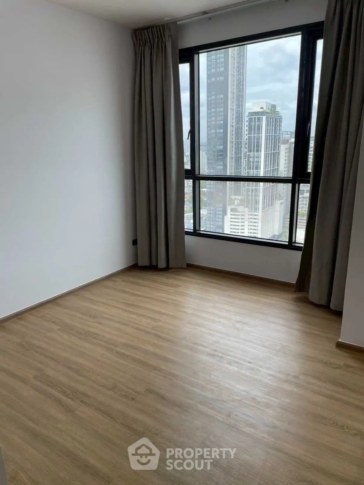 Spacious empty room with large window and city view, perfect for customization.