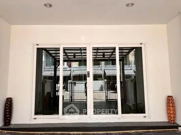 Modern building entrance with large glass doors and decorative vases, offering a sleek and inviting look.