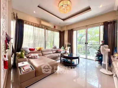 Spacious living room with elegant decor and garden view, featuring a large sectional sofa and chandelier.