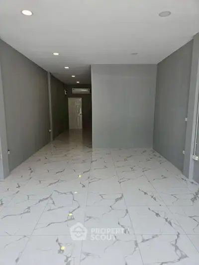 Spacious empty room with marble flooring and recessed lighting, perfect for customization.