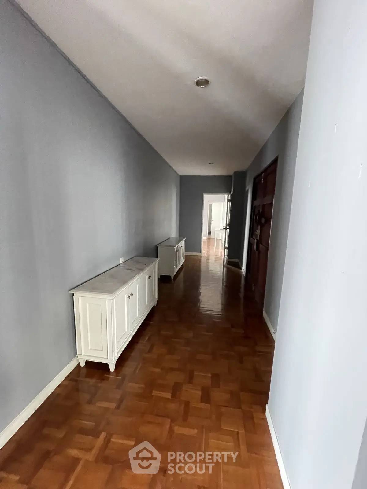 Spacious hallway with wooden flooring and elegant white cabinets.