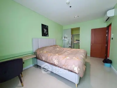 Spacious bedroom with modern decor and green walls, featuring a comfortable bed and sleek furniture.