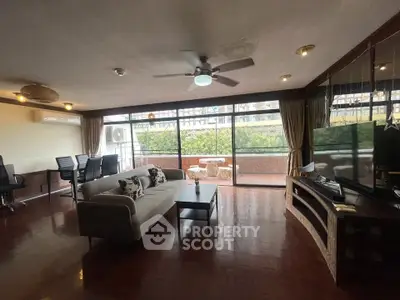 Spacious living room with large windows and balcony access, featuring modern furniture and abundant natural light.