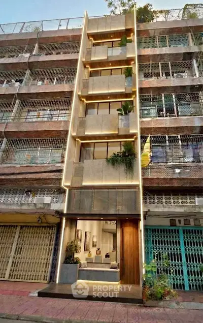 Stunning modern building facade with unique lighting and lush greenery accents.