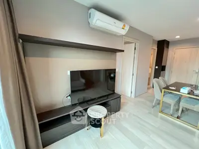 Modern living room with sleek TV setup and dining area in stylish apartment.