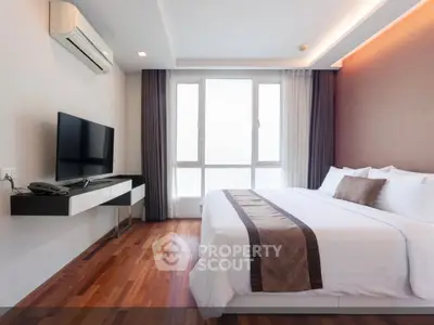 Modern bedroom with hardwood floors, large window, and sleek furnishings in a stylish apartment.