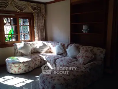 Cozy living room with floral sofa and elegant curtains, perfect for relaxation.