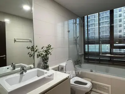 Modern bathroom with sleek fixtures and large window in urban apartment.