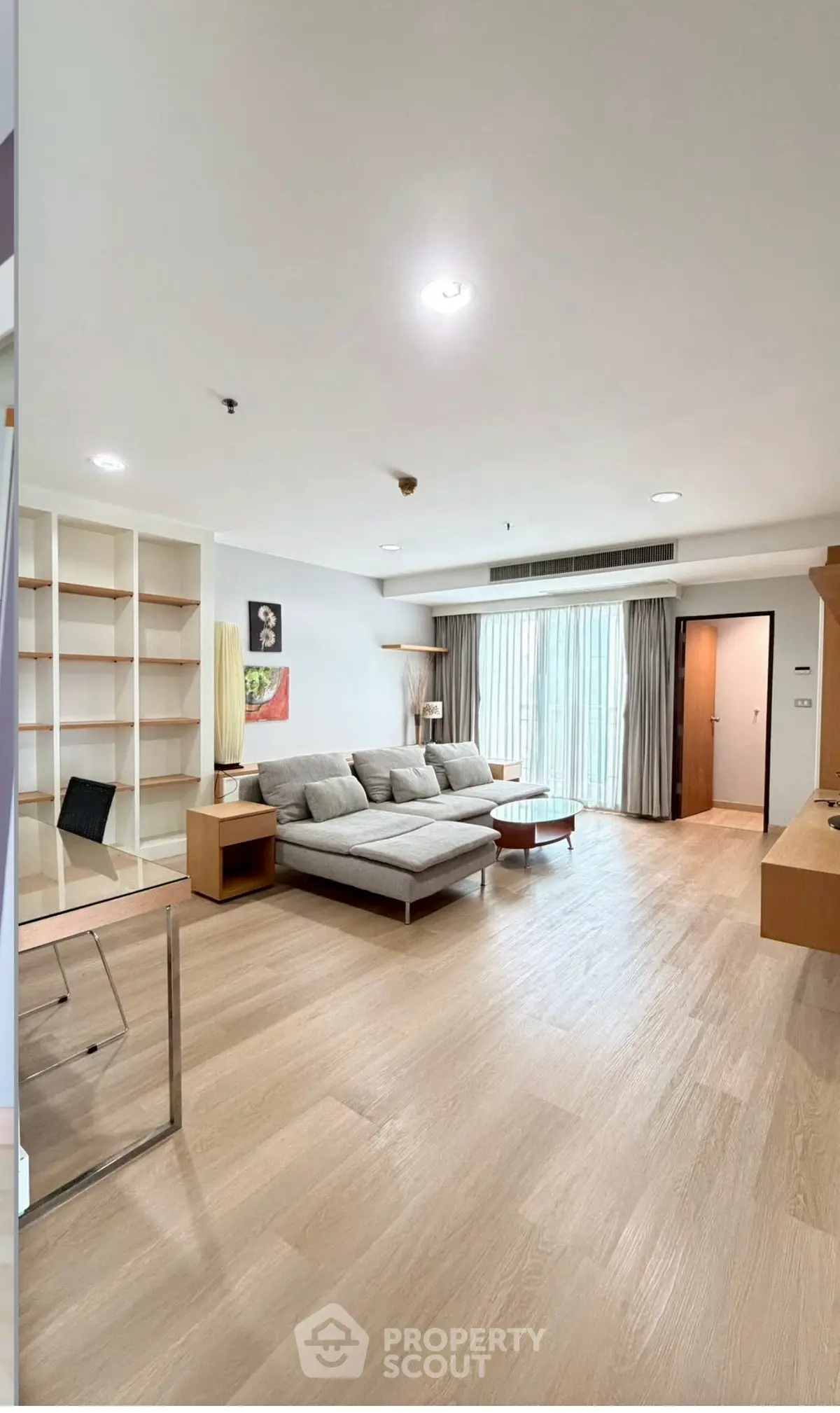 Spacious modern living room with wooden flooring and large windows in a stylish apartment.
