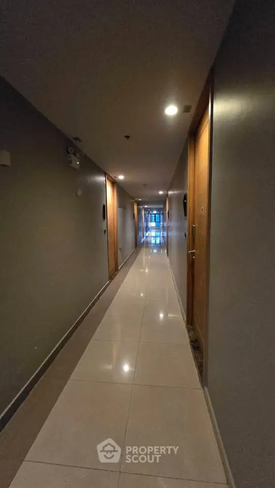 Modern apartment corridor with polished floors and ambient lighting.