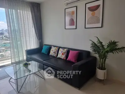 Modern living room with city view, stylish decor, and sleek black sofa.