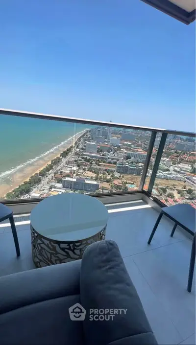 Stunning high-rise balcony view overlooking the ocean and cityscape, perfect for urban living.
