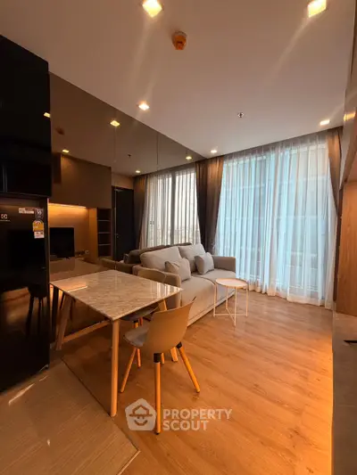 Modern living room with elegant decor and natural light, featuring a cozy sofa and dining area.