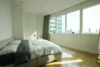 Spacious bedroom with large windows offering stunning city views and abundant natural light.