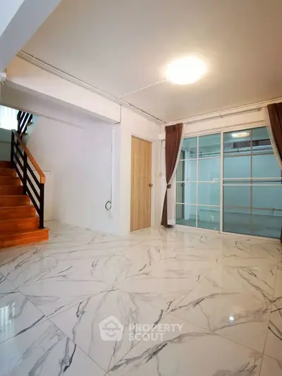 Spacious modern living room with marble flooring and large windows for natural light.