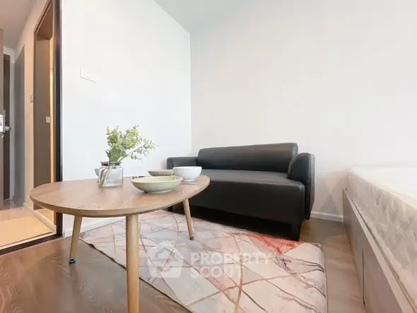 Modern living room with sleek black sofa and stylish coffee table in cozy apartment.