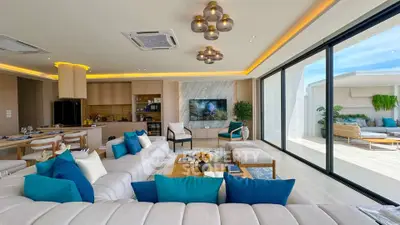 Luxurious open-plan living room with modern decor and large glass doors leading to a spacious balcony.