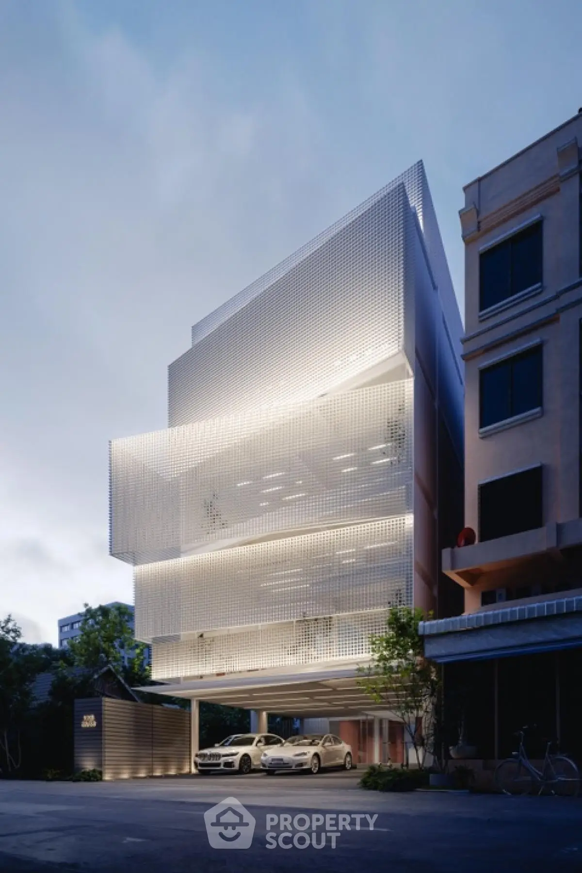 Modern architectural building with illuminated facade and parking area