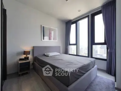 Modern bedroom with large windows offering city views, featuring a stylish bed and elegant decor.