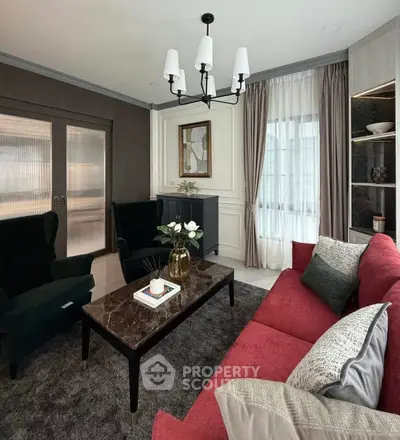 Elegant living room with red sofa, modern chandelier, and stylish decor