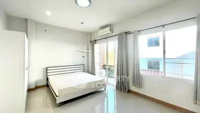 Bright and airy bedroom with large windows and balcony access in modern apartment.