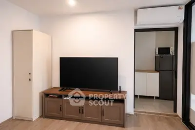 Modern living room with sleek TV setup and view into a compact kitchen area.