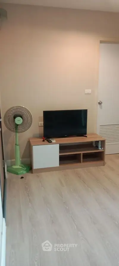 Cozy living room with modern TV stand and fan, perfect for relaxation.