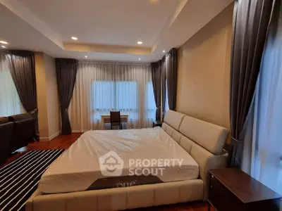 Luxurious bedroom with elegant curtains and modern furniture in a spacious apartment.