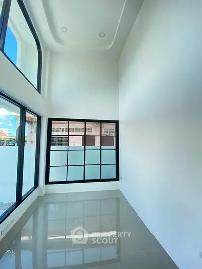 Spacious modern room with high ceilings and large windows offering abundant natural light.