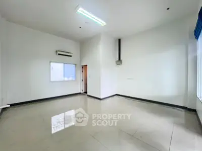 Spacious empty room with tiled flooring and large window, ideal for customization.