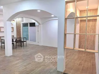 Spacious open-plan living area with modern wooden flooring and stylish arches.