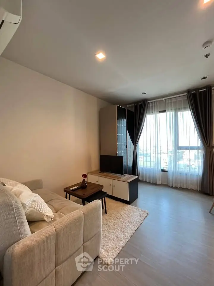Modern living room with cozy sofa, stylish decor, and large window offering natural light.