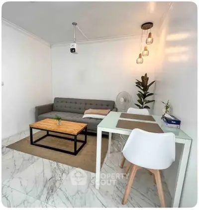 Modern living room with stylish furniture and marble flooring, featuring a cozy sofa and elegant lighting.