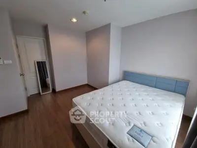 Spacious bedroom with modern design and hardwood floors, featuring a comfortable bed and minimalist decor.