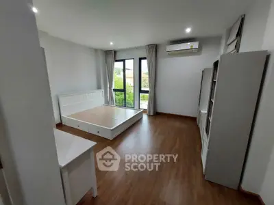Spacious bedroom with large windows and wooden flooring, featuring modern minimalist design.