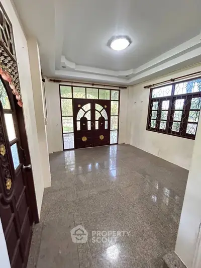 Spacious room with elegant wooden doors and large windows offering natural light.