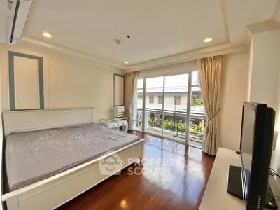 Spacious bedroom with balcony access and elegant wooden flooring