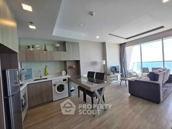 Modern open-plan living room with kitchen, featuring ocean view and stylish furnishings.