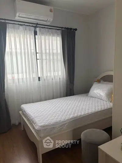 Cozy bedroom with natural light, featuring a single bed and elegant curtains, perfect for a serene retreat.