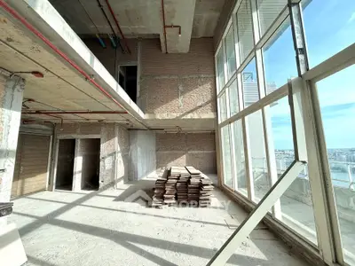 Spacious unfinished high-rise apartment with floor-to-ceiling windows and city view, ideal for customization.