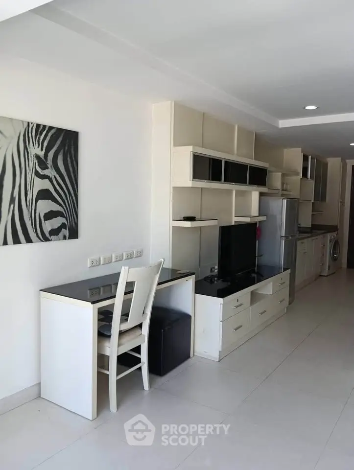 Modern living room with sleek furniture and zebra artwork, featuring a compact kitchen area with appliances.