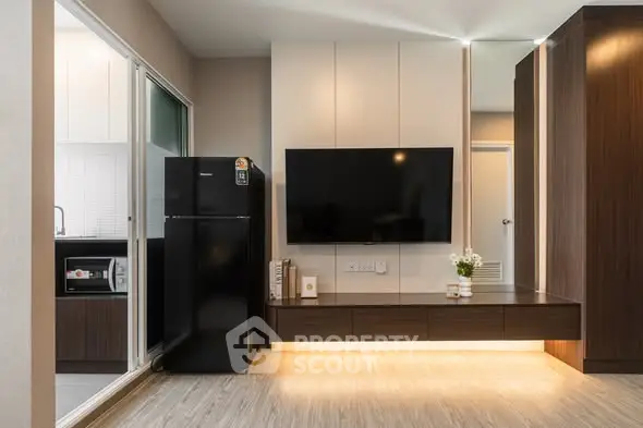 Modern living room with sleek design, wall-mounted TV, and adjacent kitchen area in a stylish apartment.