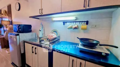 Modern kitchen with sleek cabinetry, compact appliances, and efficient lighting for a cozy cooking experience.