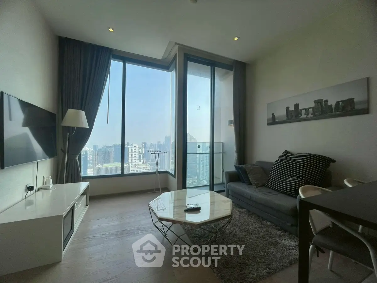Modern living room with stunning city view, featuring sleek furniture and floor-to-ceiling windows.