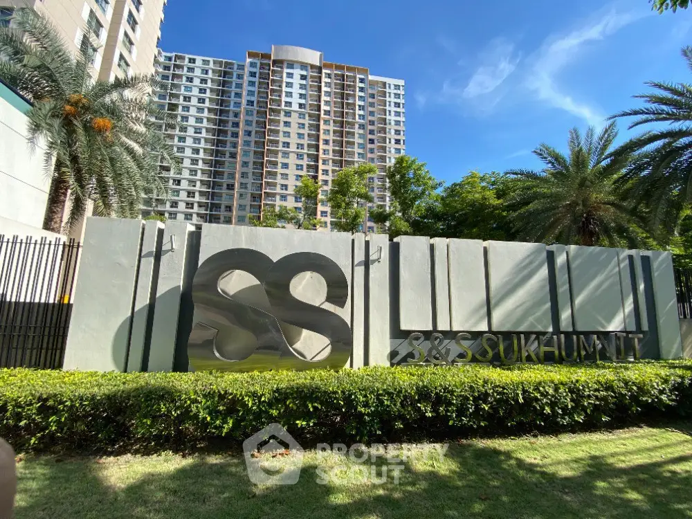 Modern condominium building with lush greenery and stylish entrance signage.