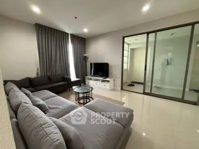 Spacious modern living room with sleek gray sofas and large TV, perfect for relaxation.