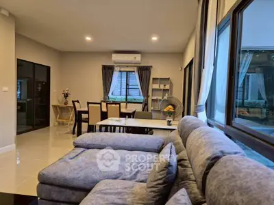 Spacious modern living room with large windows and elegant dining area, perfect for family gatherings.