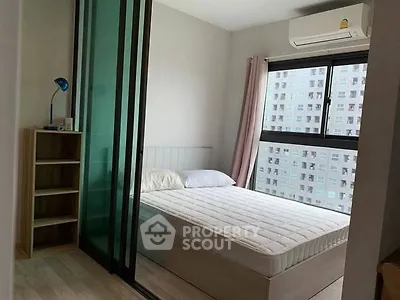 Modern bedroom with large window and air conditioning in urban apartment.